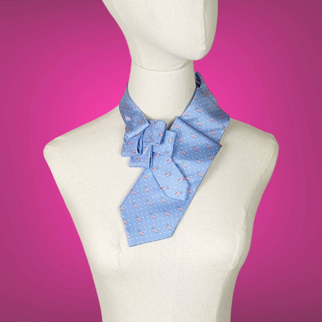 a pale blue pleated ascot with a small pink whale print. It's on a fabric mannequin